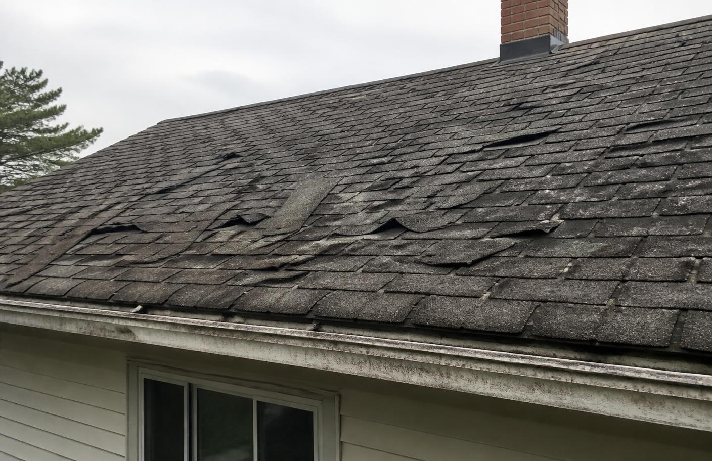 Deteriorated asphalt shingle roof before metal roof replacement